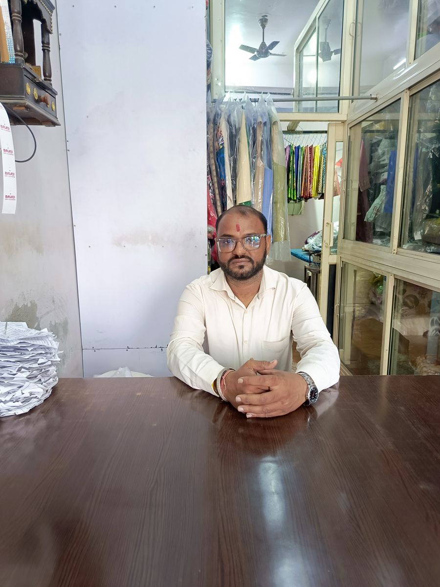 The owner of Balaji Dry Cleaners at the counter of the Janakpuri shop